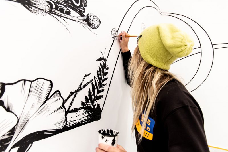 A person hand painting a a detail of a mural.