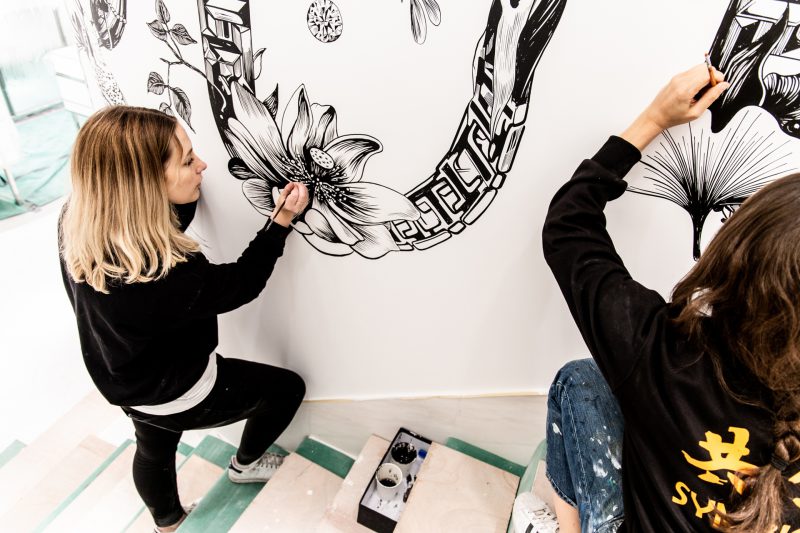 Two people painting a mural in a stairwell