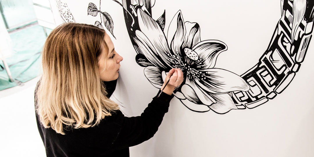 Woman hand painting a flower on a wall